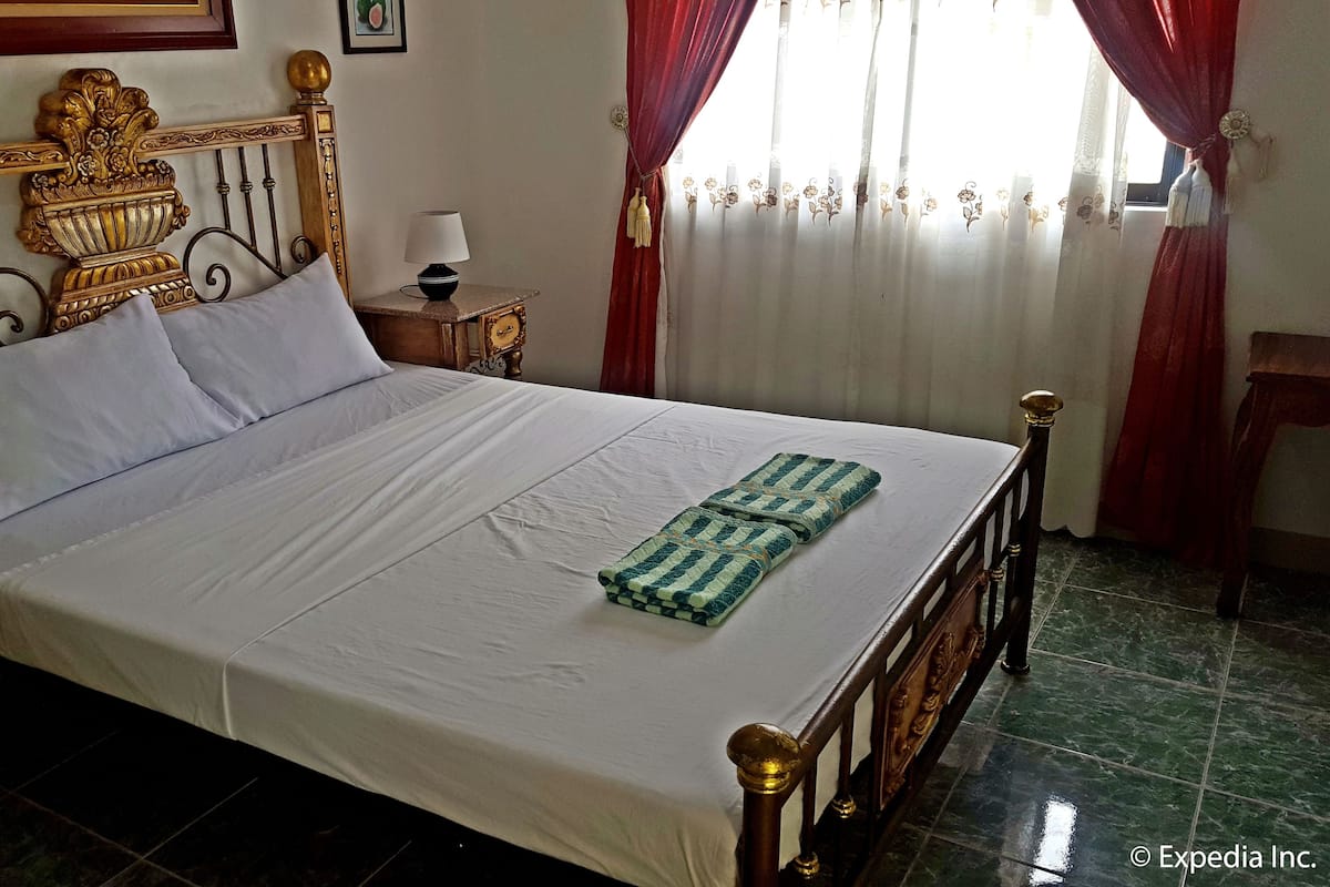 A neatly made bed with white linens, a decorative headboard, and a bedside table with a lamp.