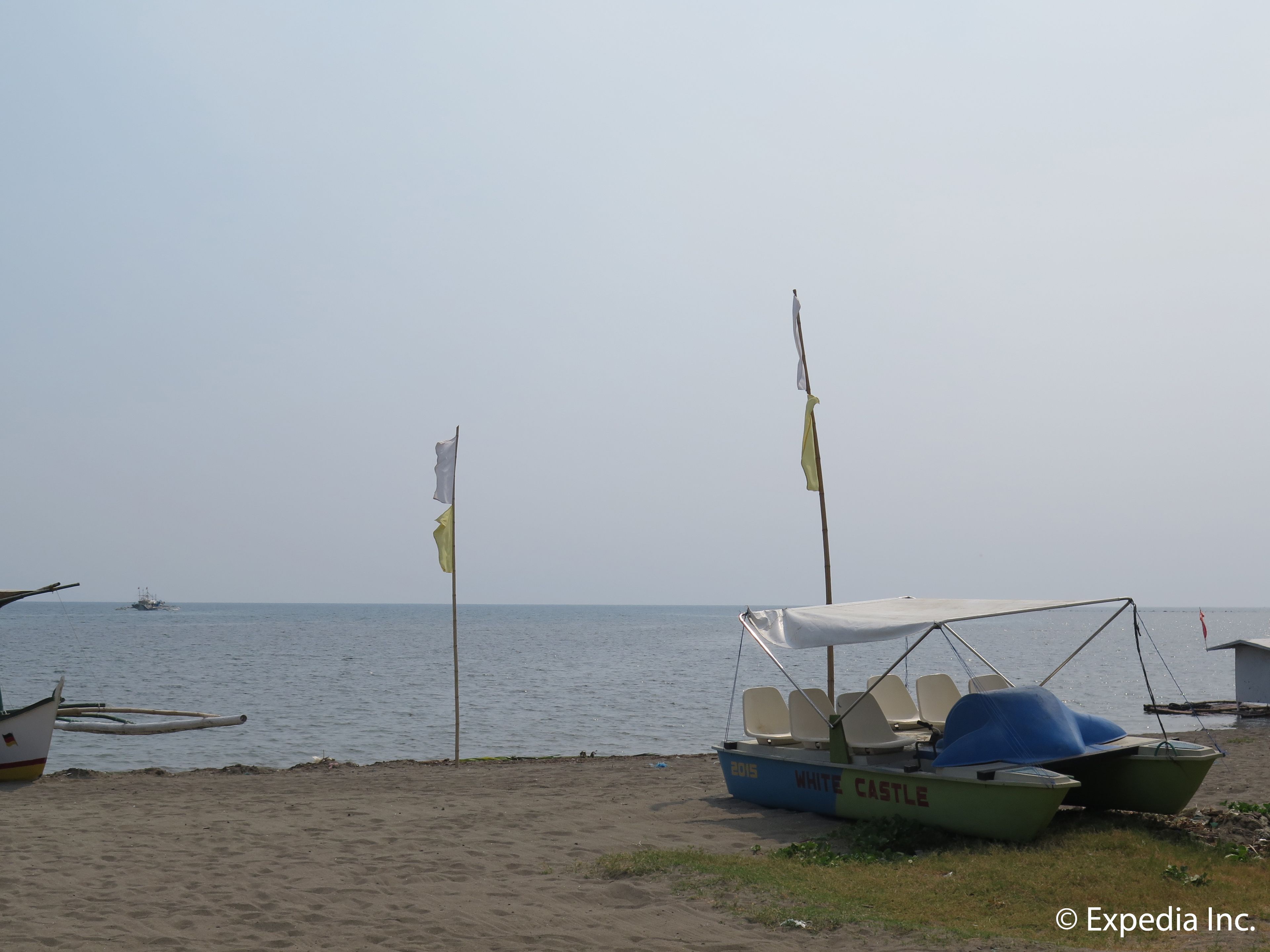 Una playa con un bote llamado "WHITE CASTLE" y otro barco al fondo.