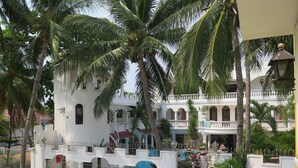 Un edificio de estilo colonial blanco con balcones y una entrada protegida por una reja.