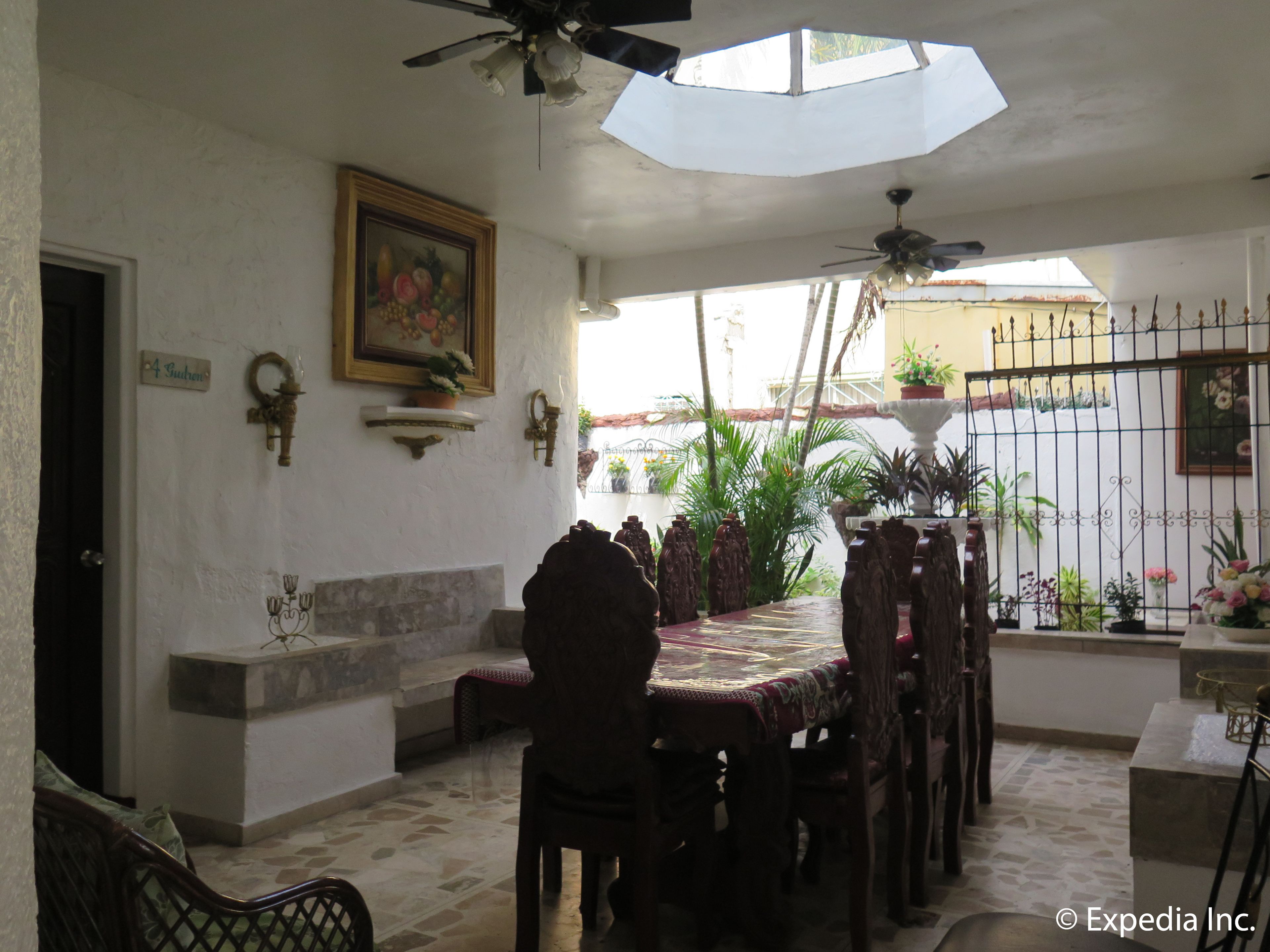 Zona pranzo con tavolo e sedie, una ventola a soffitto, una pianta in vaso e un lampadario a parete.