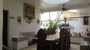 Zona pranzo con tavolo e sedie, una ventola a soffitto, una pianta in vaso e un lampadario a parete.