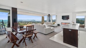 Una sala de estar moderna con comedor, una isla de cocina y un amplio ventanal con vistas panorámicas.