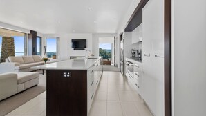 Una cocina moderna con una isla central, muebles blancos y un ventanal con vistas panorámicas.