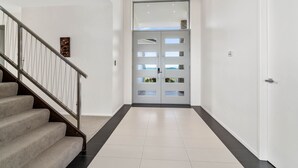 Un interior moderno con una escalera, un doble puerta con paneles de vidrio y un piso de baldosas limpias.