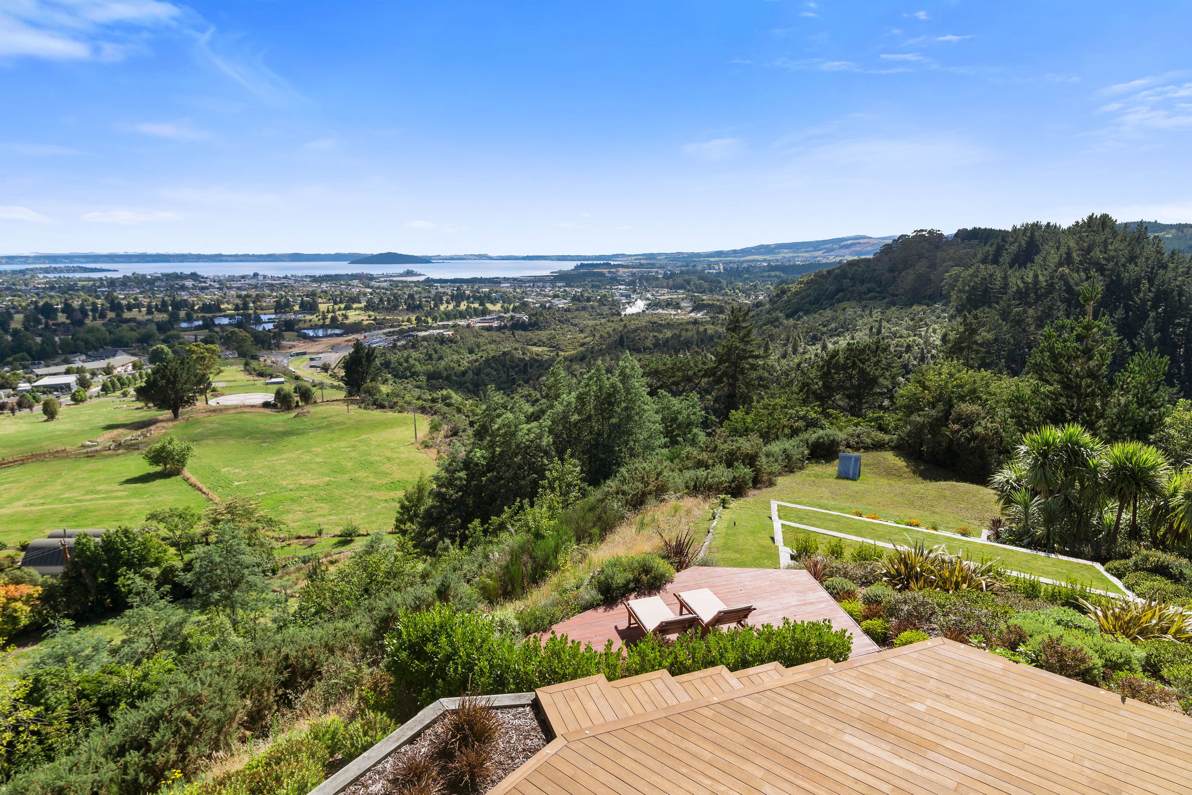 A view of a lush green landscape with a wooden deck and outdoor seating area.