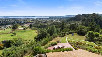 A view of a lush green landscape with a wooden deck and outdoor seating area.