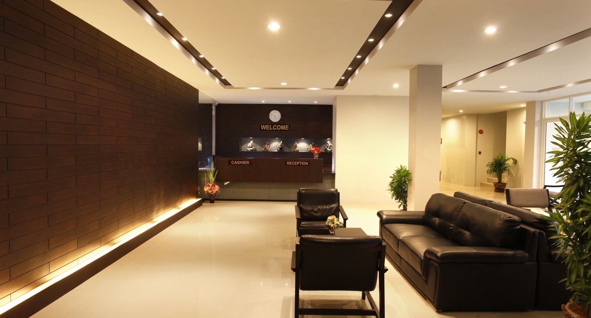 A modern reception area with a brick wall, a reception desk labeled "WELCOME," and a seating area with a sofa and chairs.