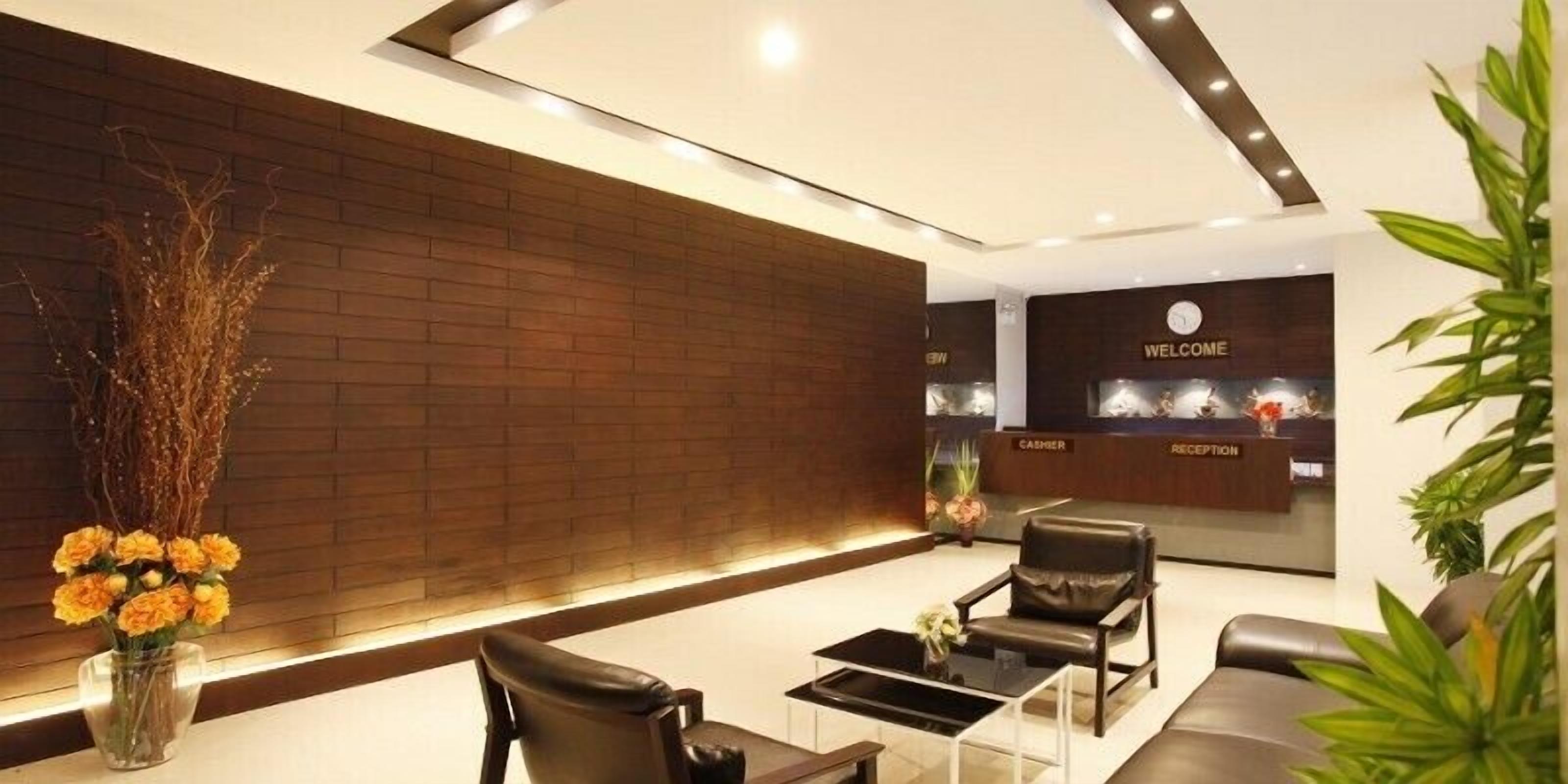 A modern reception area with a reception desk, leather seating, and a decorative vase of flowers.