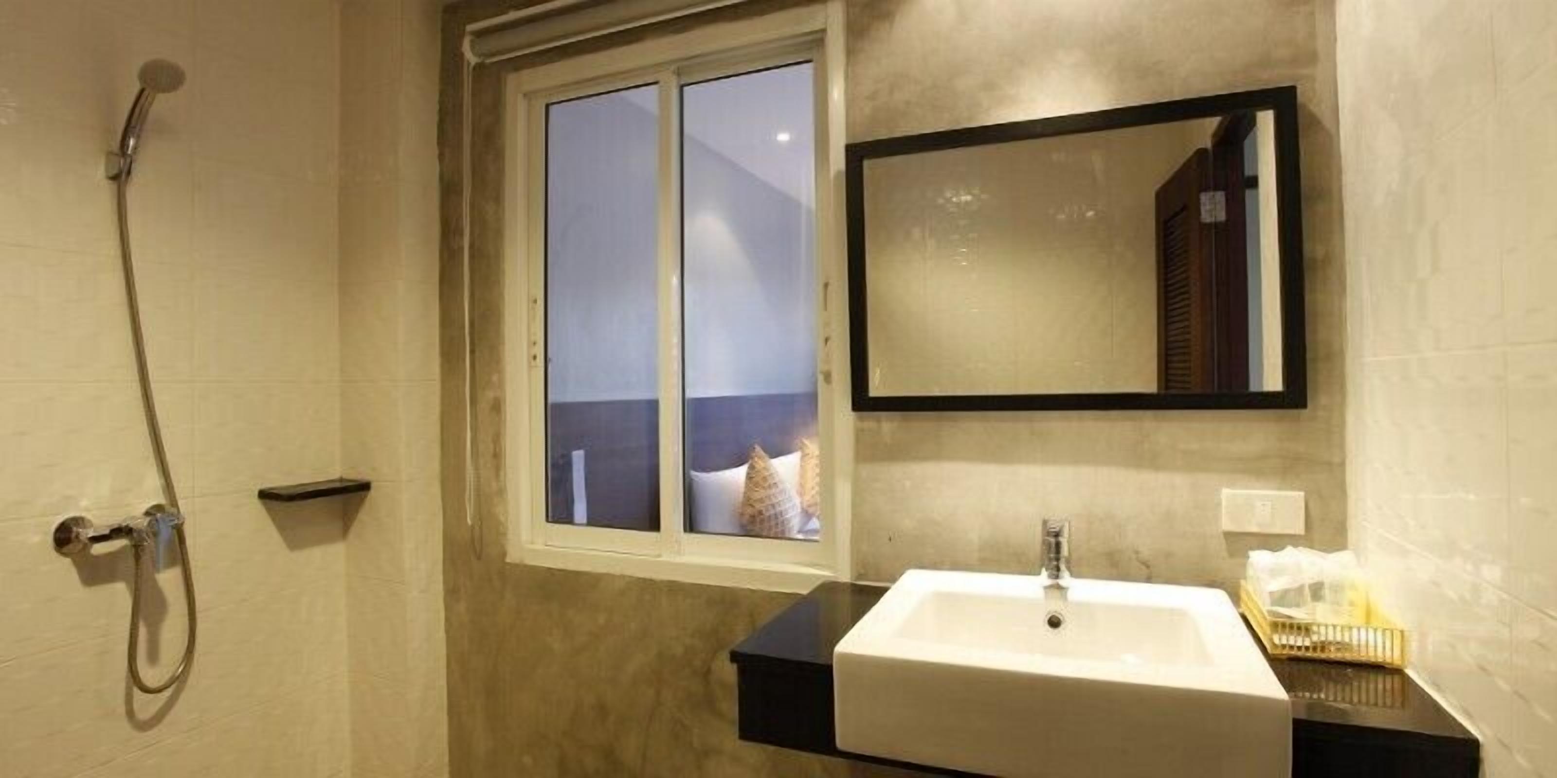 Un baño con ducha, lavabo, espejo y ventana.