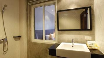 Une salle de bain avec une douche, un lavabo, un miroir et une fenêtre.