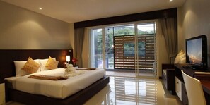 A hotel room with a large bed, a desk, a television, and a sliding glass door to the outside. - Nize Hotel (Ratsada)