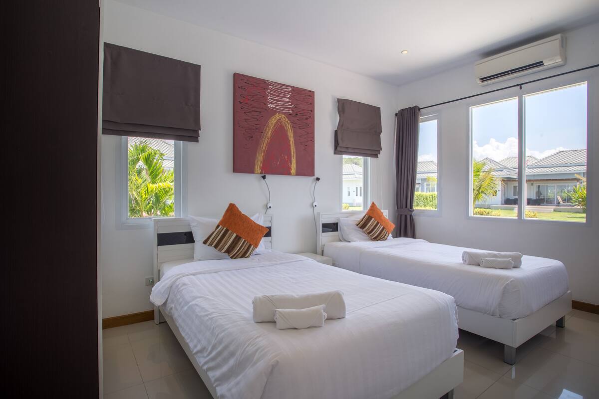 Une chambre d’hôtel avec deux lits, une grande fenêtre et un tableau au mur.