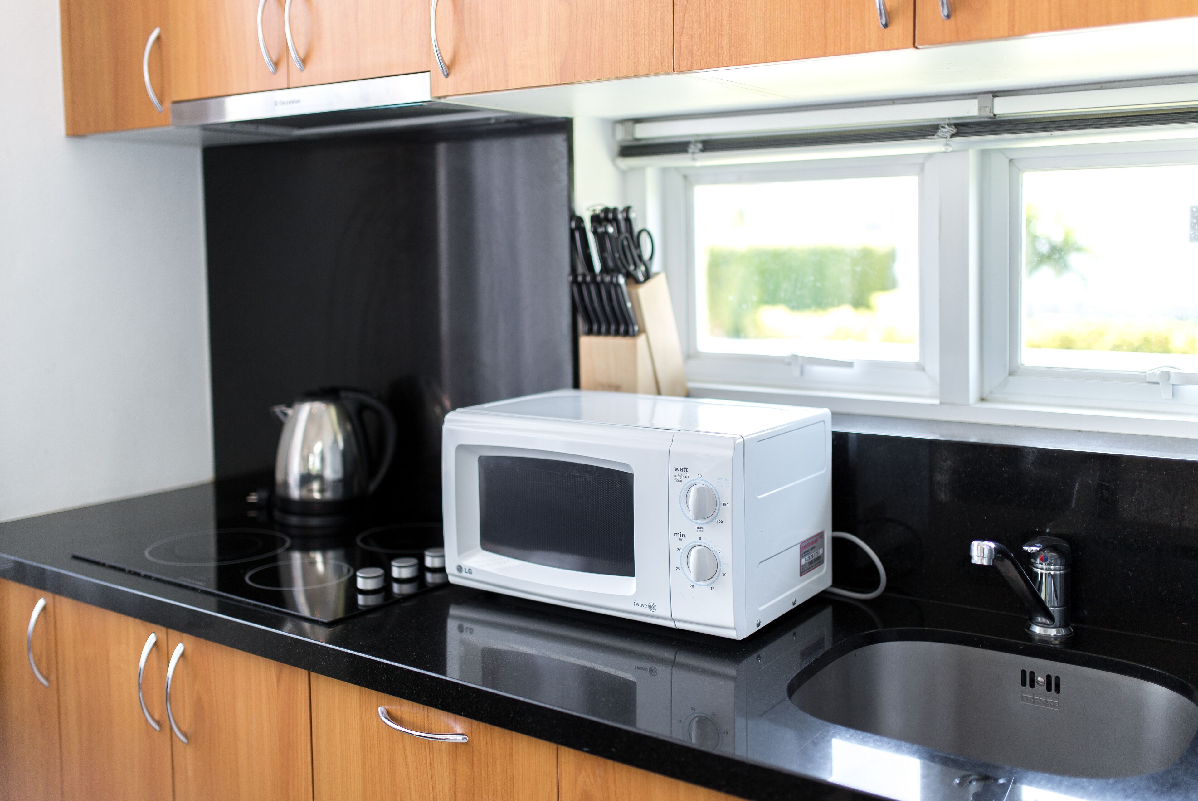 A kitchen with a microwave, stove, sink, and wooden cabinets.