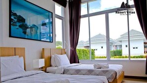 A hotel room with two beds, a large window with curtains, and a painting of a mountainous landscape. - Black Mountain Resort (Hua Hin)
