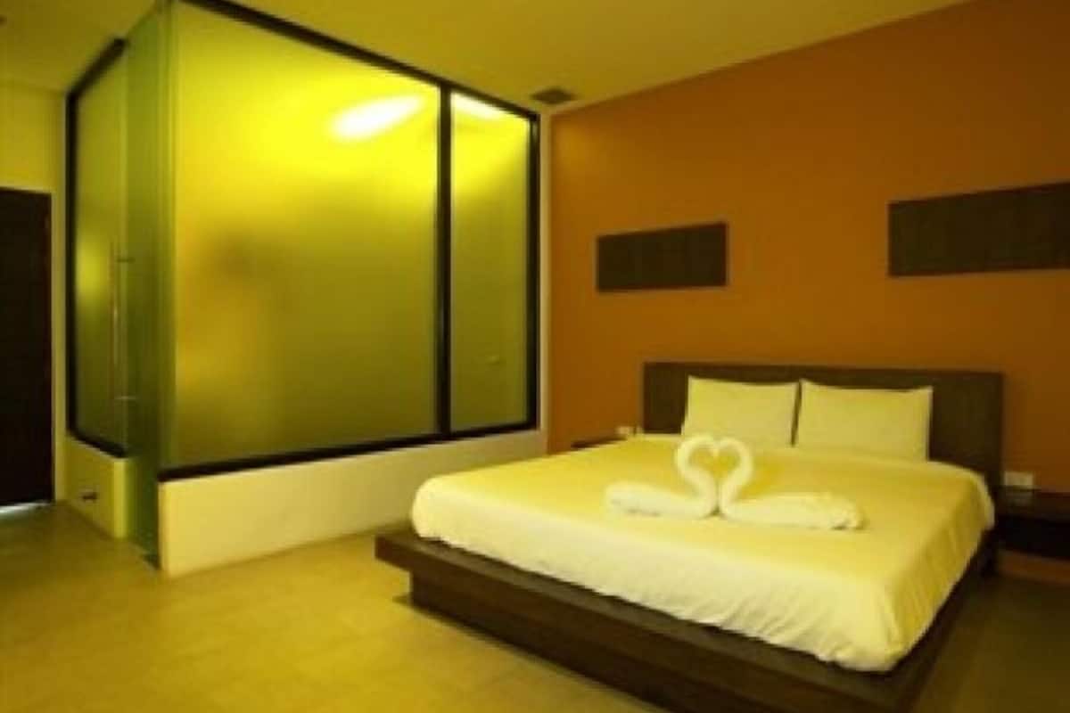 Habitación de hotel con una cama grande, un espejo y un televisor montado en la pared.