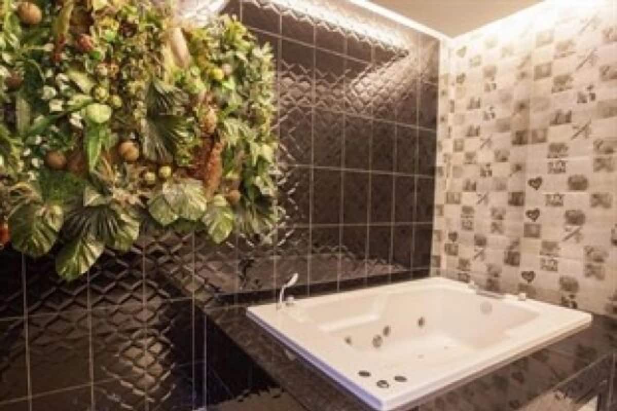 Un baño con una bañera grande, una pared con un diseño geométrico y una pared con un diseño de corazón.