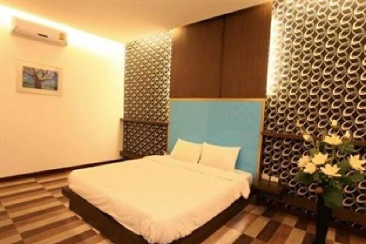Una habitación de hotel con una cama, un papel tapiz estampado y un suelo de madera.