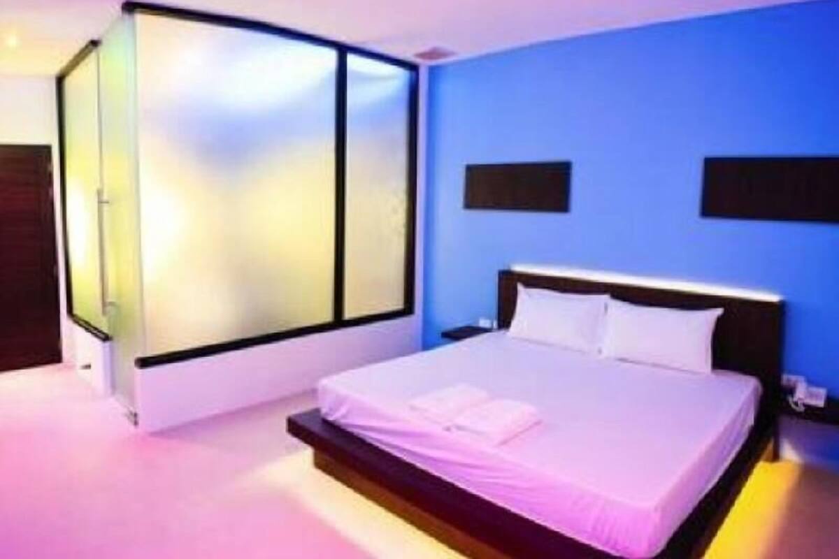 Un dormitorio con una cama, una mesita de noche y un ventanal con persianas.