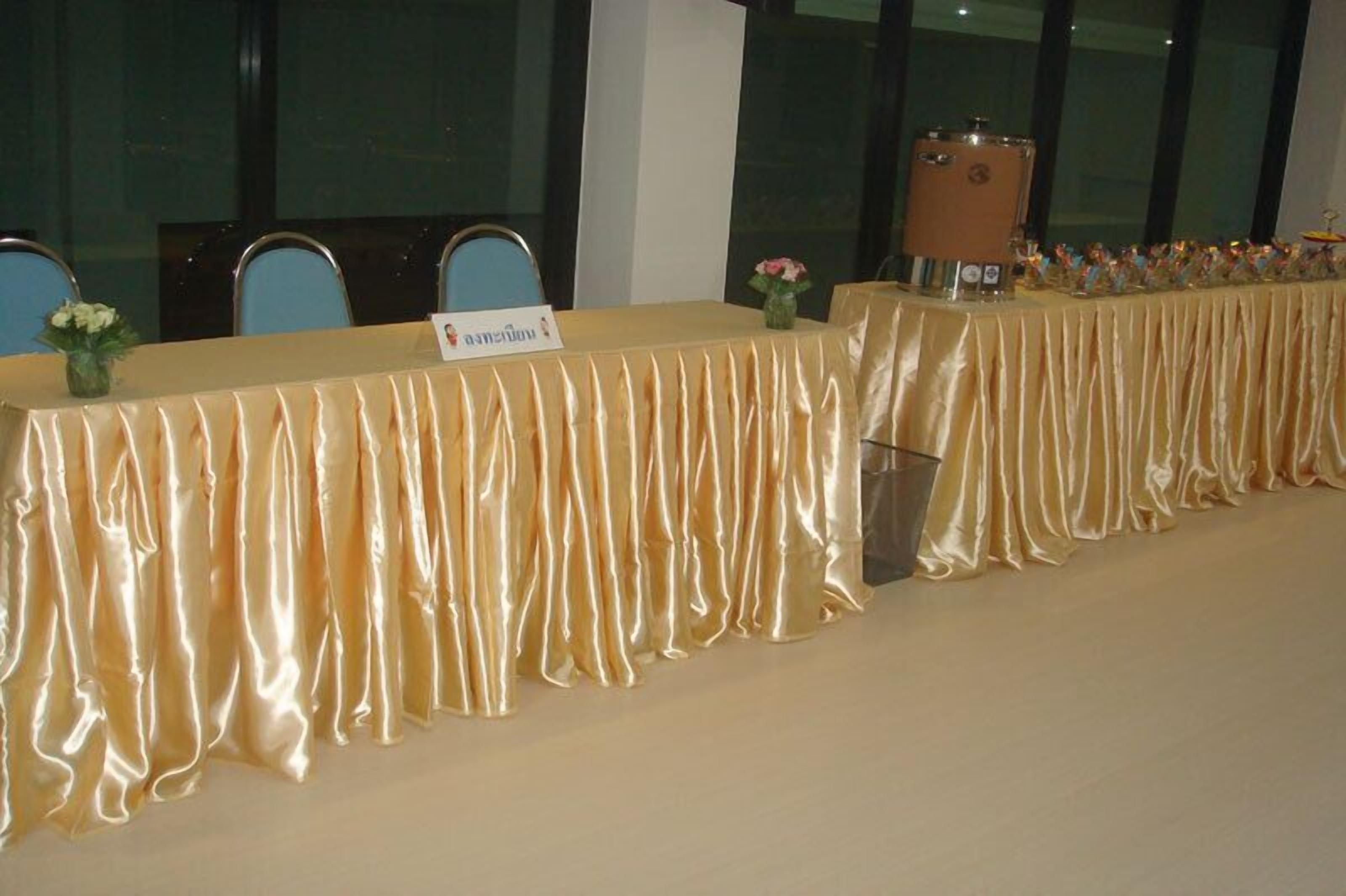 A banquet table with a satin drape, name placard, and a decorative item on the side.
