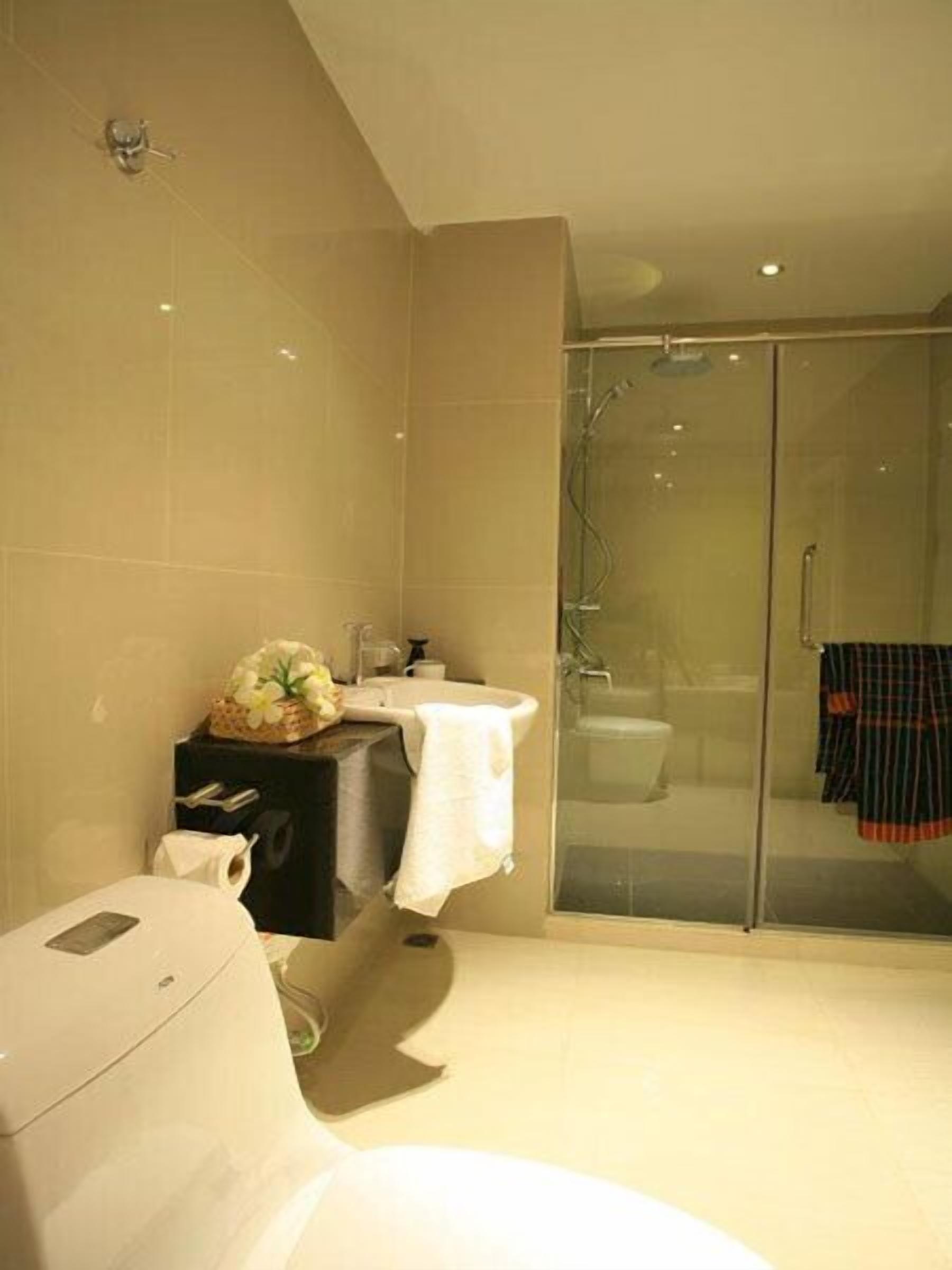 A modern bathroom with a large mirror, a white sink, and a glass-enclosed shower.