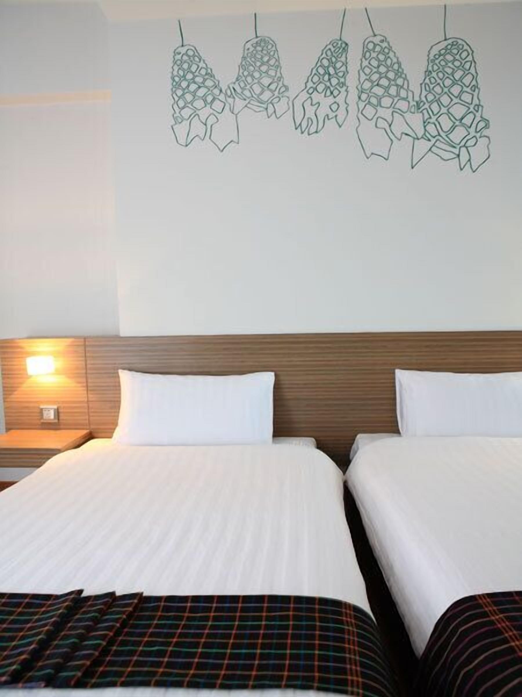 A hotel room with two beds, a wooden headboard, and a wall decoration of hanging objects.