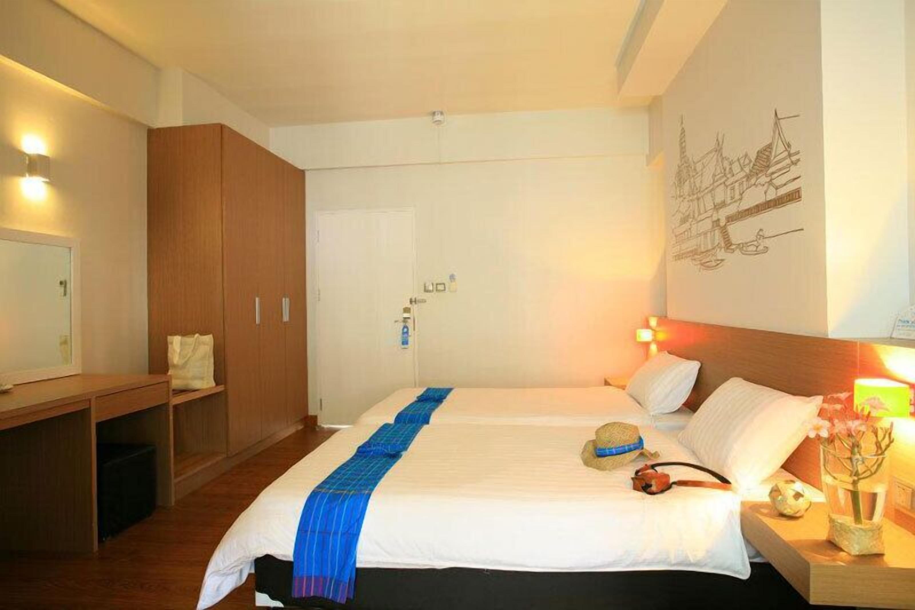 Ett hotellrum med en stor säng, en garderob i trä och ett konstverk som hänger på väggen.