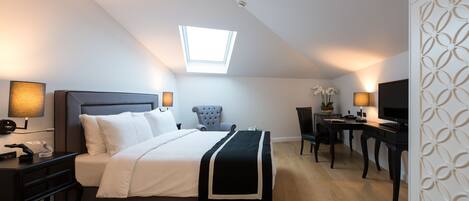 Una habitación de hotel moderna con cama, escritorio, silla, tragaluz y televisión.