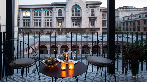 A balcony with two chairs, a table with a fruit bowl, candles, and a view of a historic building with a dome. - Régie Ottoman Istanbul (Istanbul)