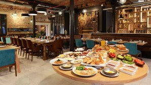 Een restaurant met diverse gerechten op een grote tafel, omringd door stoelen en tafels.