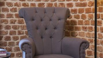 A tufted armchair with a high back, positioned against a brick wall.