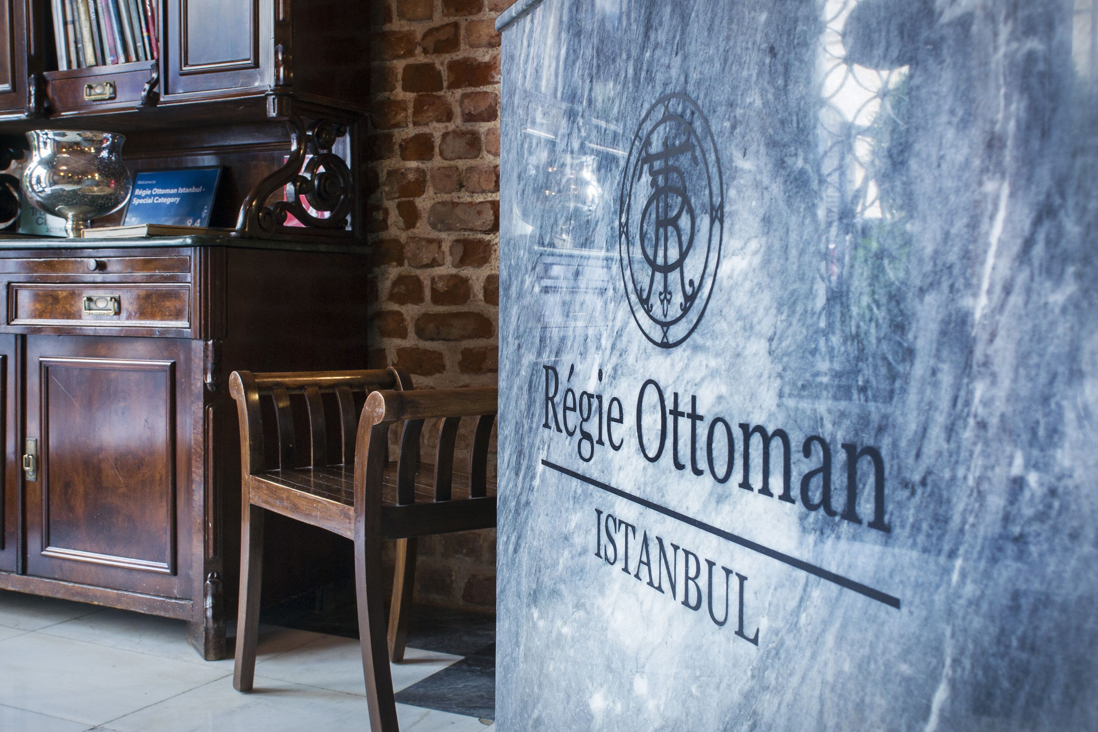 Una placa de mármol con la inscripción "Régie Ottoman Istanbul" y una silla frente a un armario de madera.