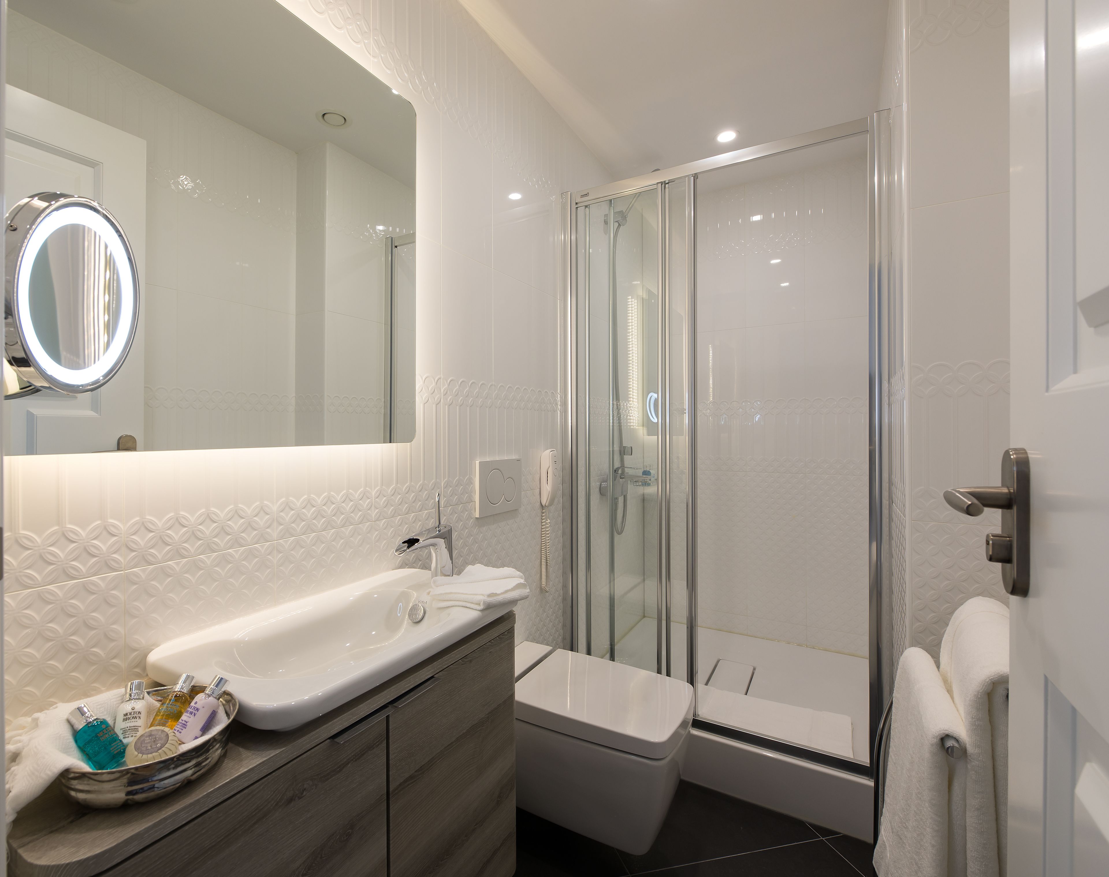 A modern bathroom with a glass-enclosed shower, a vanity with a sink, and a mirror.