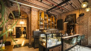 A bar area with a brick wall, shelves of bottles, a bar counter, and green bar stools. - Régie Ottoman Istanbul (Istanbul)