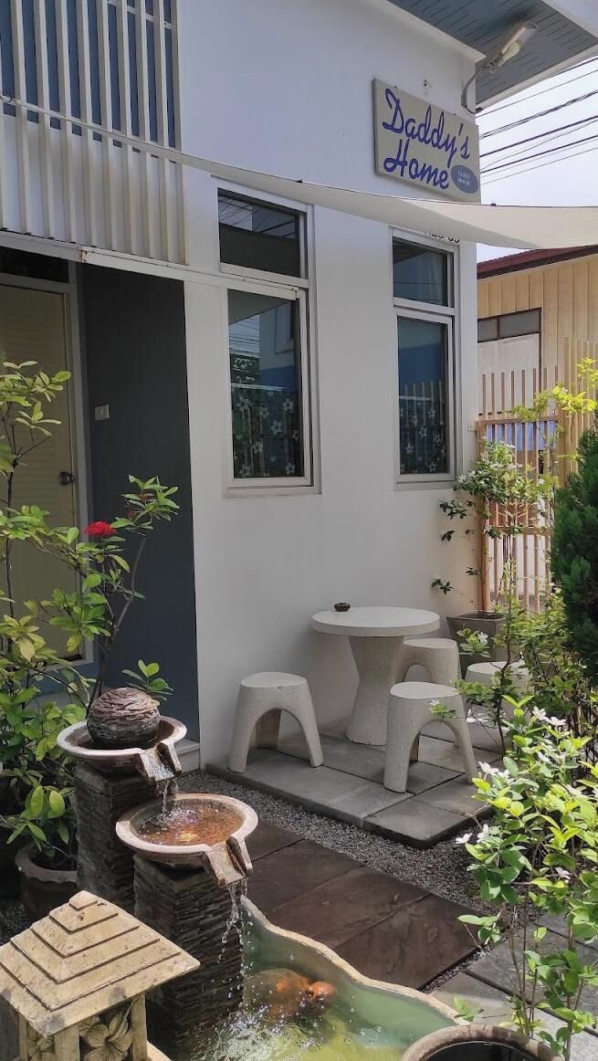 Un bâtiment sur lequel est apposée une enseigne indiquant « Chez Papa », et une petite zone extérieure aménagée avec des tabourets et une table.