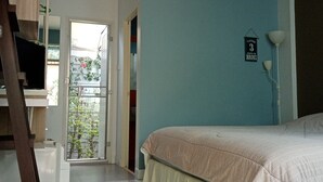 Een slaapkamer met een bed, een airconditioner, een wandlamp en uitzicht op het balkon.