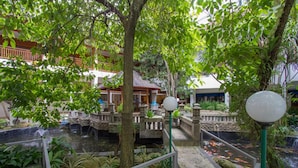 Un jardin intérieur agrémenté d’un bassin à carpes koï, de sentiers en pierre et de structures traditionnelles en bois.
