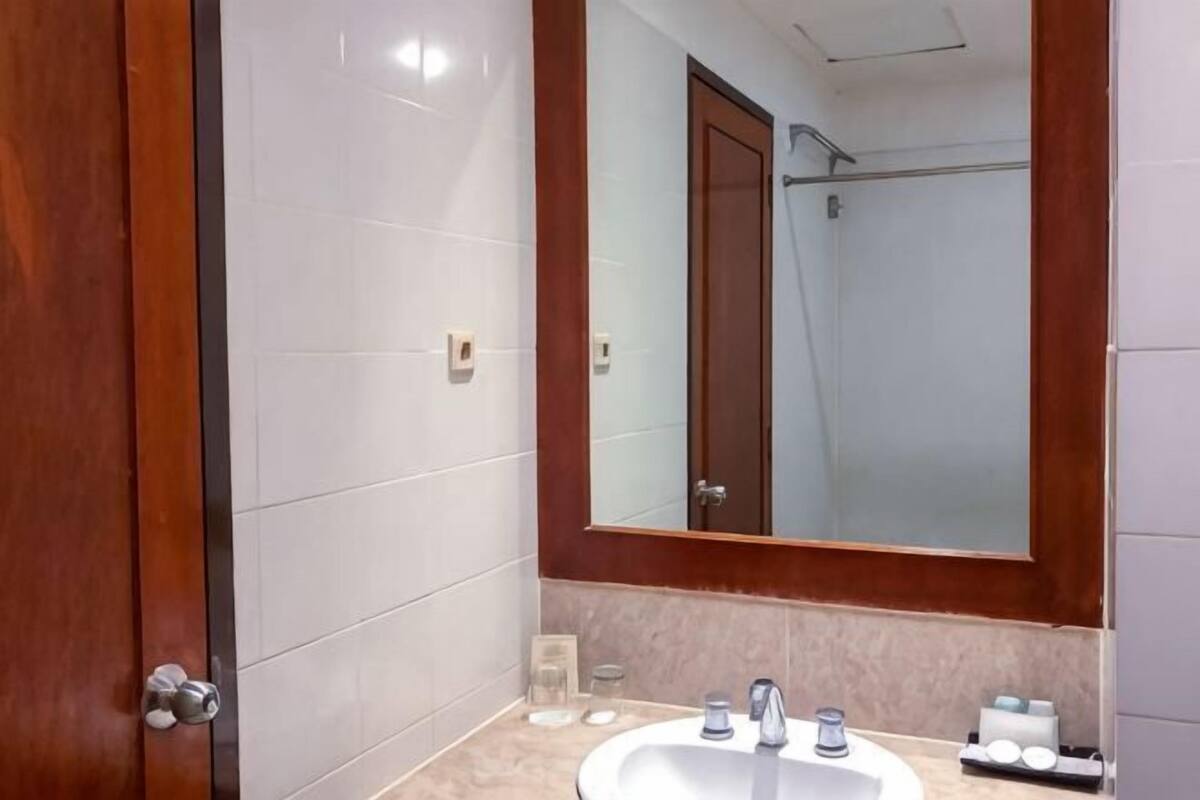 Une salle de bain avec un grand miroir, un lavabo et une douche.