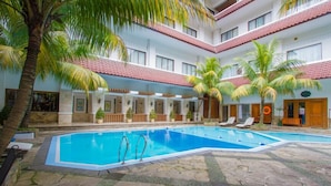Un hôtel doté d’une piscine centrale, de nombreux balcons et de palmiers.