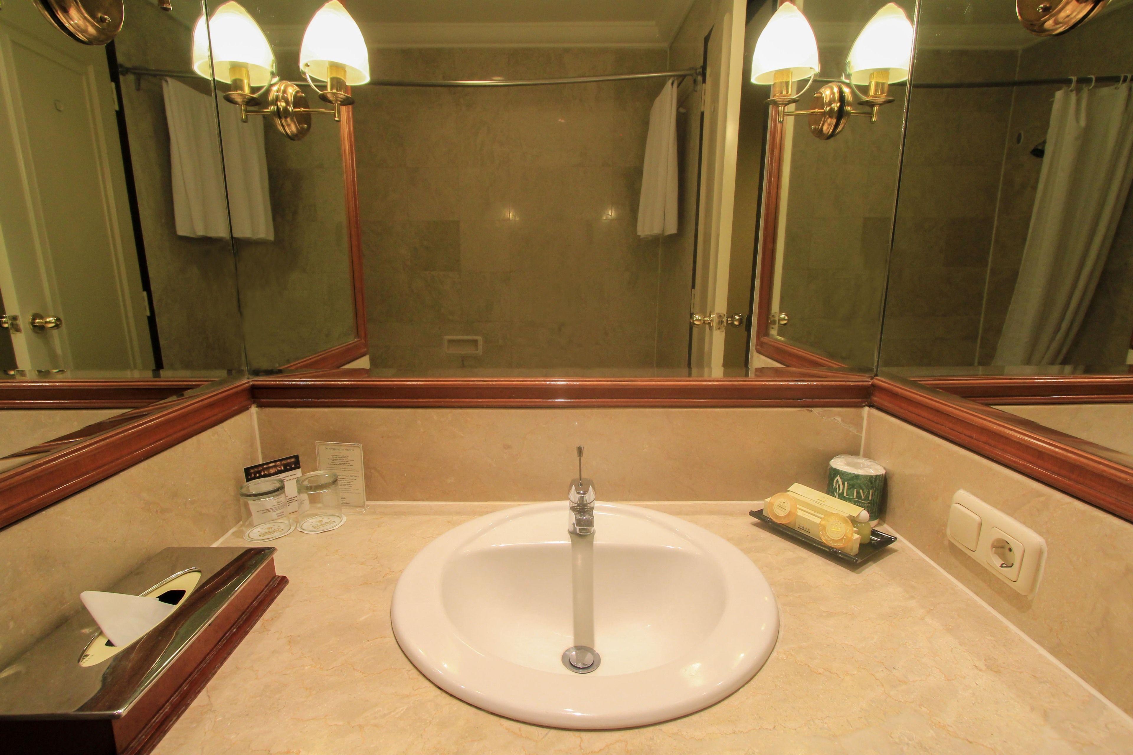 A bathroom with a sink, mirror, and toiletries.