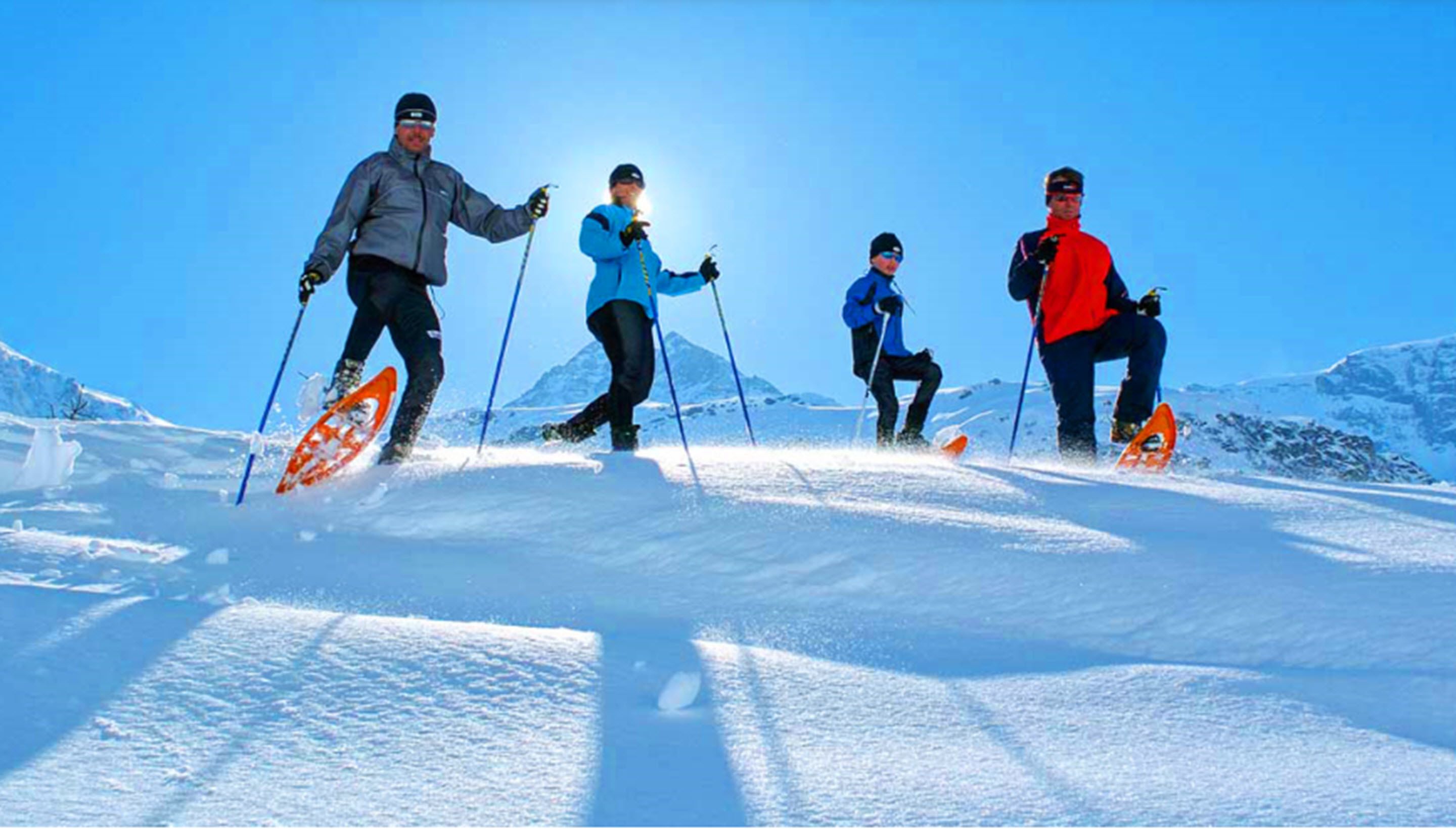 Un grupo de esquiadores en una pendiente nevada bajo cielos despejados.