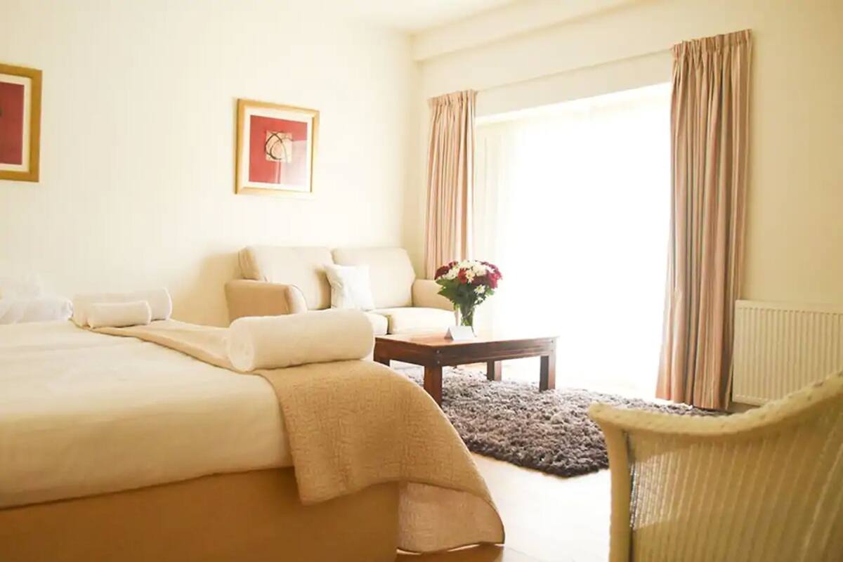 Una habitación de hotel con una cama grande, un sofá, una mesita y una silla.