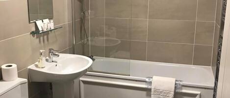 A modern bathroom with a toilet, sink, and bathtub.