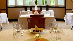 A dining area with tables set for a meal, featuring a central dish with a garnish, surrounded by empty wine glasses and water glasses. - Bridge of Orchy Hotel (Bridge of Orchy)