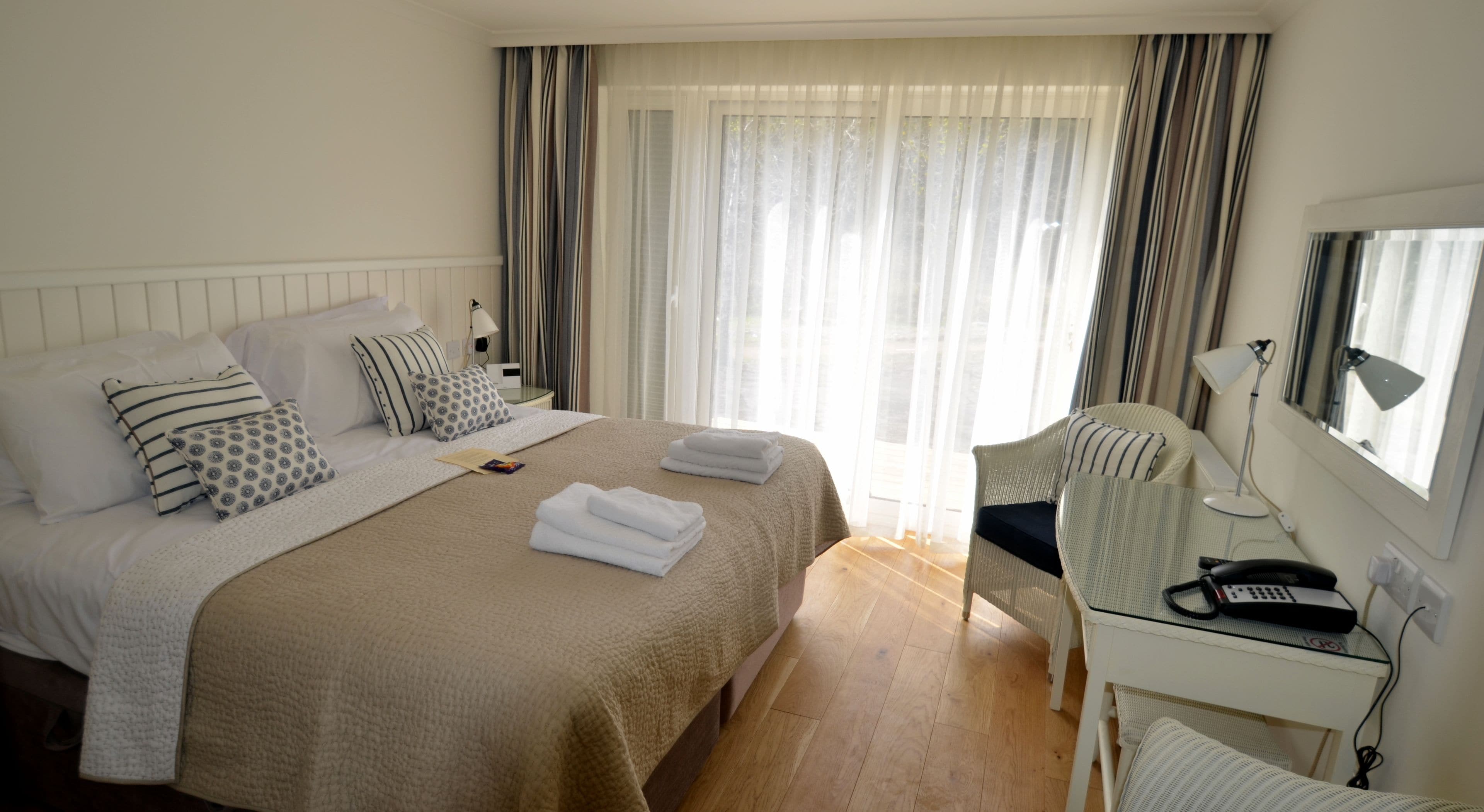 Una habitación de hotel con una cama grande, un escritorio con teléfono y una silla.