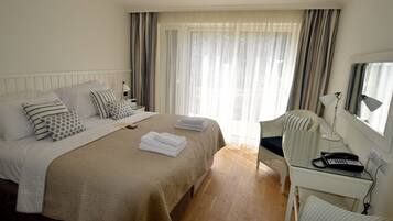 Una habitación de hotel con una cama grande, un escritorio con teléfono y una silla.