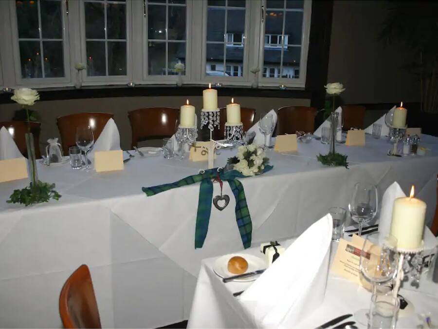 Mesa de jantar posta para um evento formal, com velas, taças e um arranjo floral.