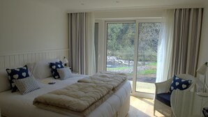 A bedroom with a large bed, two pillows, a bedside table, and a chair. - Bridge of Orchy Hotel (Bridge of Orchy)