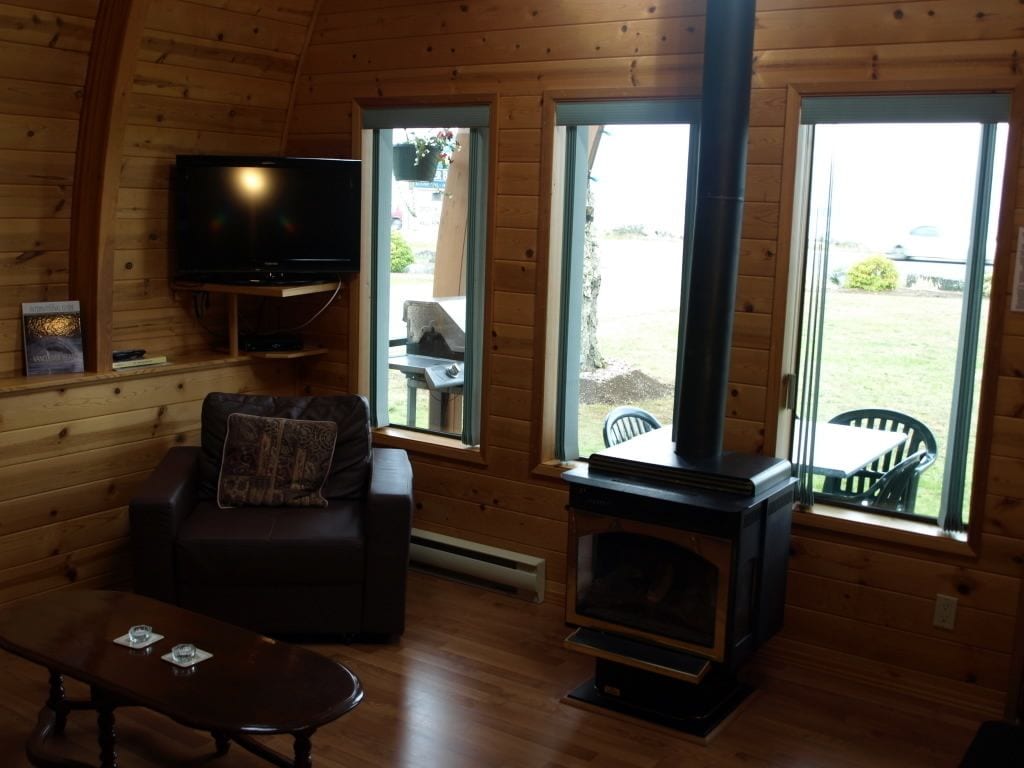 A cozy cabin interior with a fireplace, a television, a sofa, and a dining table.