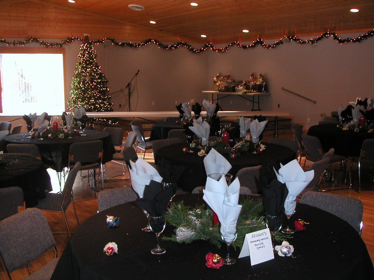 A conference room with round tables set for a meeting, a Christmas tree, and a podium.