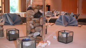 Una mesa de comedor con velas, un centro de piedras y conchas, y servilletas dobladas con cuidado.